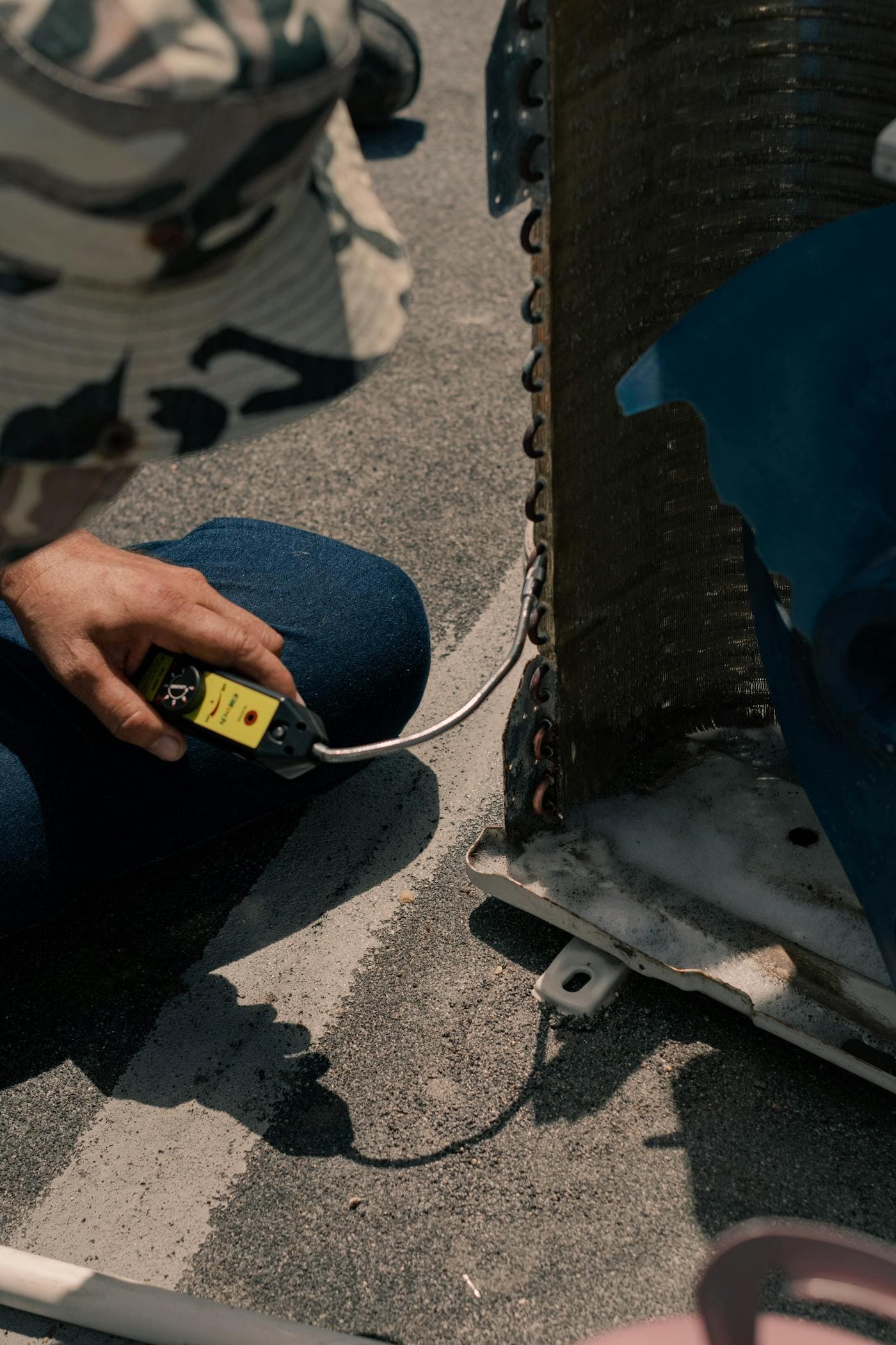 HVAC technician kneeling beside tools while servicing an air-conditioning system
