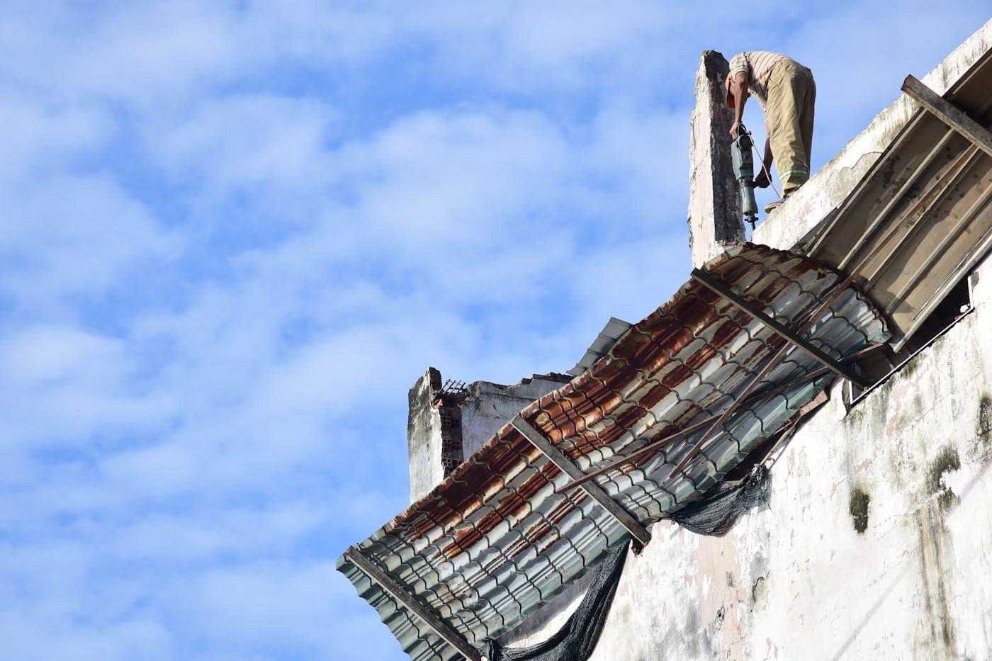 Worker repairing a residential roof under daylight
