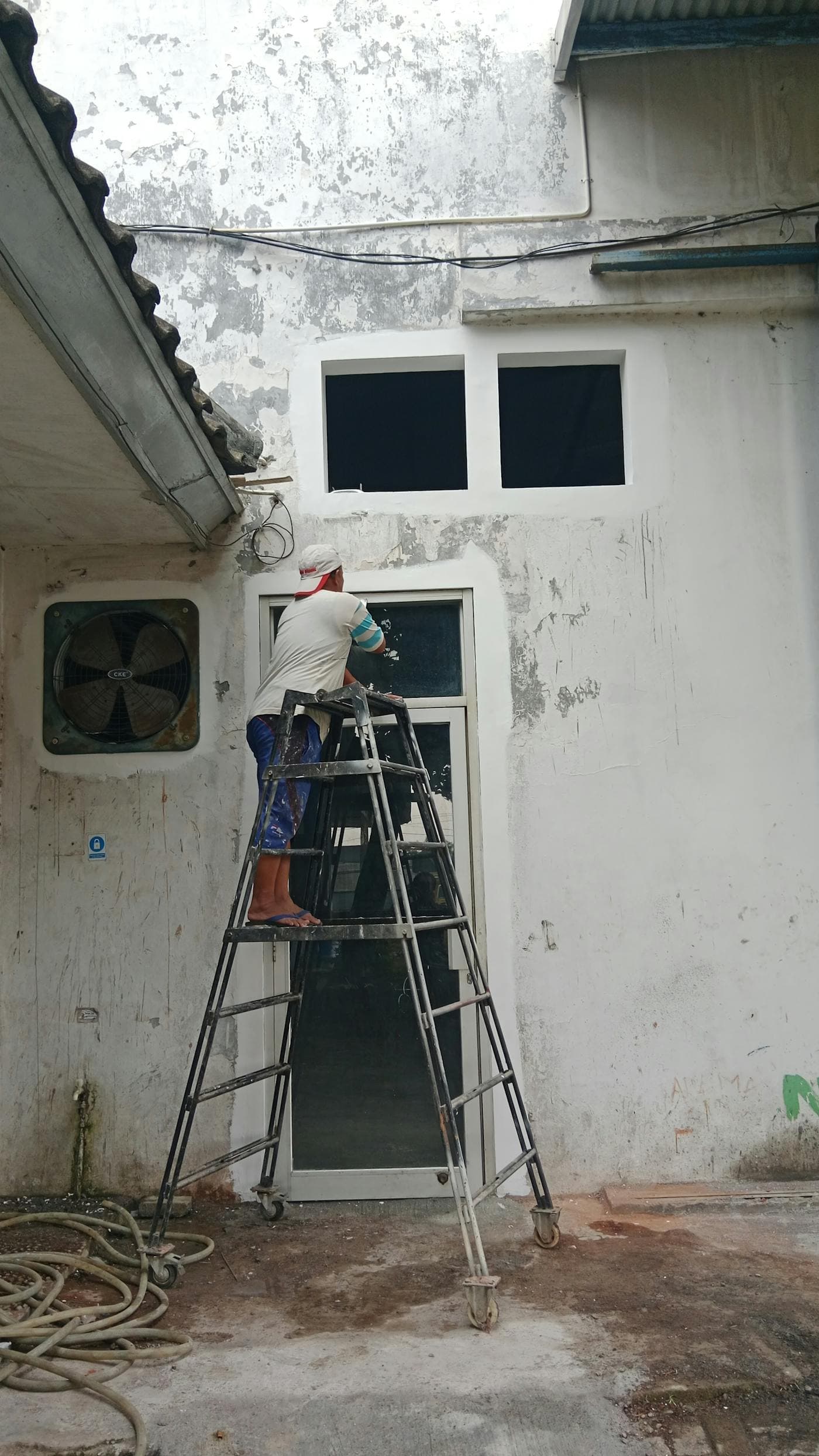Contractor on a ladder working on an exterior home facade
